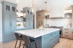 Light blue cabinets behind a granite island in a kitchen