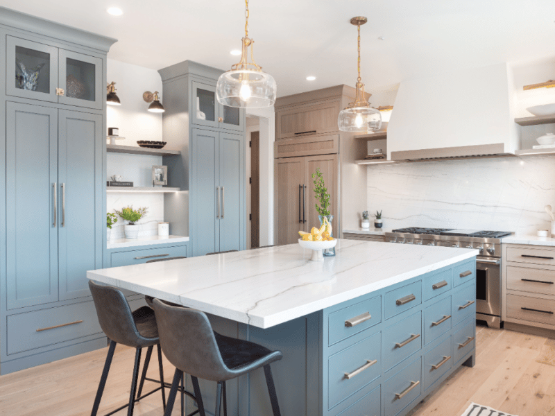 Light blue cabinets behind a granite island in a kitchen